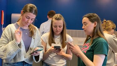 Three young women acting a scene, reading the script
