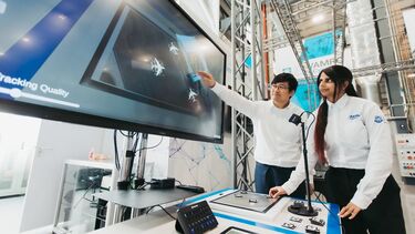 Two engineers working at a large screen