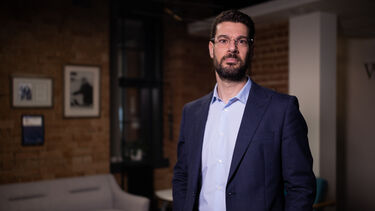 A photograph of George Panoutsos standing in a navy suit.