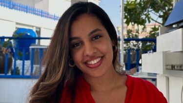 A woman with long dark hair and a red blouse smiling