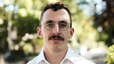 Dillon Wamsley wearing a white shirt with trees in background