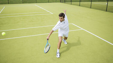 A male tennis player returning a shot.