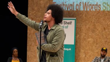 Man on stage at Off the Shelf reading