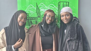 Tall women in front of green background posing for picture