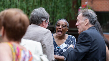 Four people laugh together outside during a reunion event