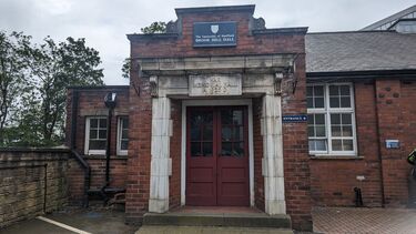 Red Double doors with top half glass, with a white stone surround and a stone plaque above the door saying War Memorial 1925