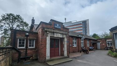 Red brick single story building with a double red door with glass and a stone decorative surround