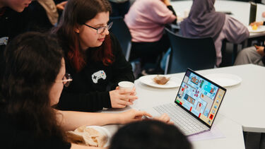 Two students looking at a video game on a laptop