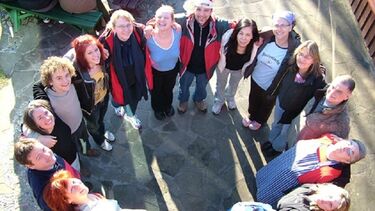 A group of people with linked arms standing in a circle and looking up at the camera