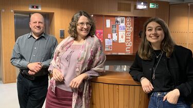 three people posing and smiling at the camera. On the door behind it says in large letters, LANGUAGES