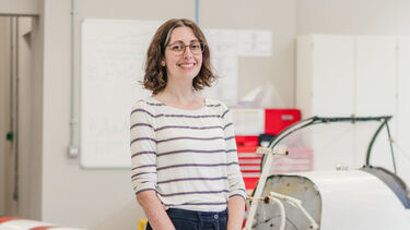 Lizzy stands in front of a small-scale airplane 