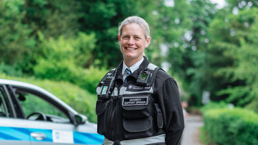 Lynette stands next to a University campus security car 