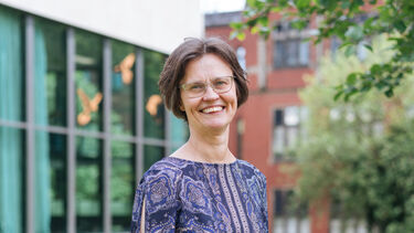 Rosanna stands on a grass bank with a building behind her 