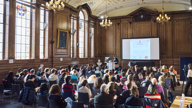 A room full of people sat watching a presentation 