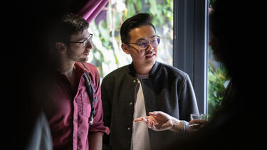 Two men standing chatting at social event 