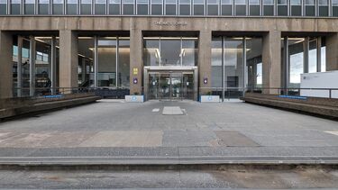 The top 2 steps and broken paving leading to an automatic door at the front of our Arts Tower building which has a lot of glass and some concrete