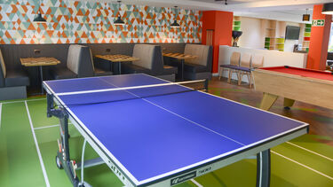 A common room with a ping pong table and booths