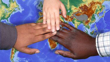 Three hands of different races over a world map.