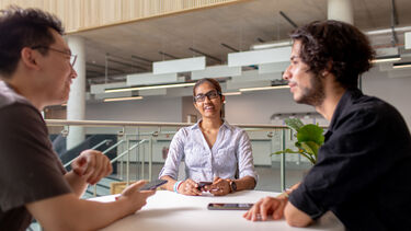Three students sat at a table chatting