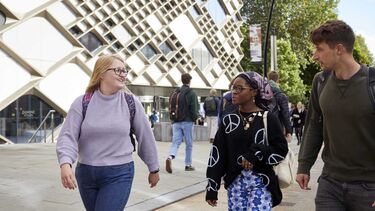 Three students walking and talking in front of the Diamond