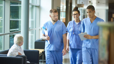 Three medical students in scrubs walking in a hospital