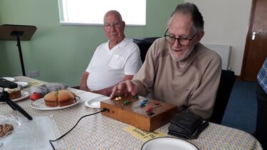 2 older men are interacting with a sound board