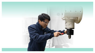 A male technician in goggles adjusting a drill press