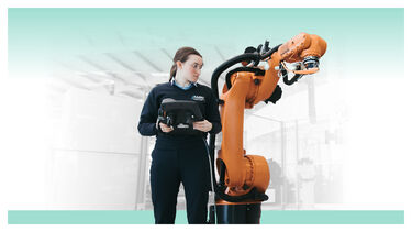 A female student controlling a large orange robotic arm
