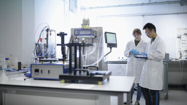 Two researchers looking at a handheld tablet in a lab