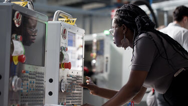 A woman standing in front of a machine checking settings
