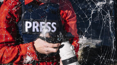A press photographer in front of smashed glass