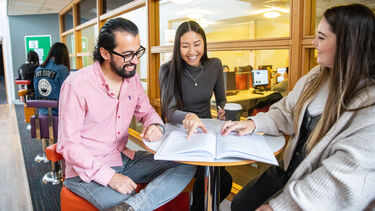 Smiling student sat around a table 