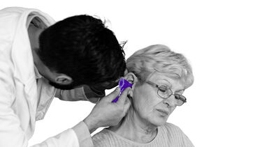 A doctor looks into a womans ear using an otoscope