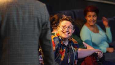 Two people are talking and smiling whilst sat in a cinema