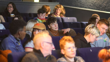 Lots of people are sat in a cinema chatting before the film