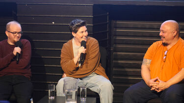 Two people are talking on a panel in front of a cinema screen