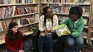 A young girl reading a book in the children's section of a library
