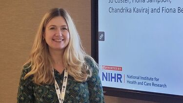 This is a picture of Jo Coster stood next to a powerpoint presentation