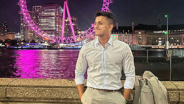 Arjun Nair stood on the bank of the River Thames. The London Eye is in the background.