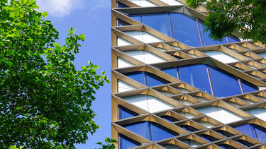 Diamond building against a blue sky with clouds and green trees