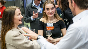 2 students talk with an older man during a networking event
