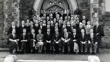 A group of 30-40 scholars in black and white, seated outside in a formal photograph