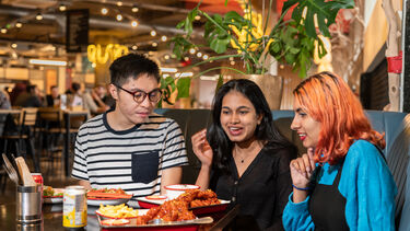 a group of three students sat in eating and chatting 