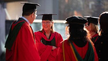 PhD graduates standing outside in sun talking
