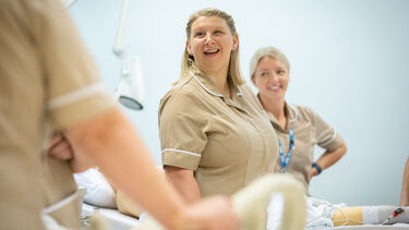 Nurses in beige uniforms working on a patient ward