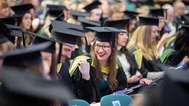Graduates sat in hall looking happy