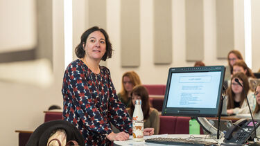 A lecturer teaching at the front of a lecture theatre