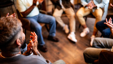 Community group seated in a circle, clapping