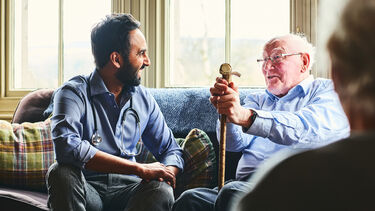Researcher sitting with elderly study participant, smiling