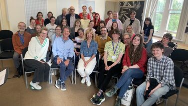 group of people sat on chairs smiling. IN the middle Claudia de Breij, Dutch stand up and singer. 